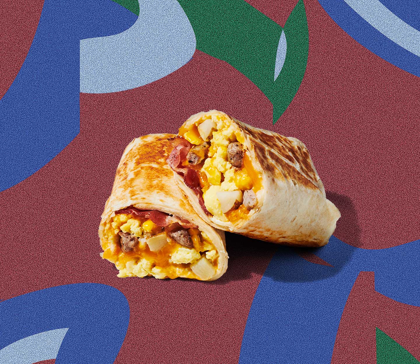 A breakfast wrap cut in half and stacked on top of itself, displaying mix of ingredients inside.